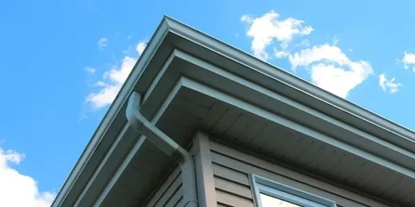 Looking up at the roof of a house with a blue sky in the background.
