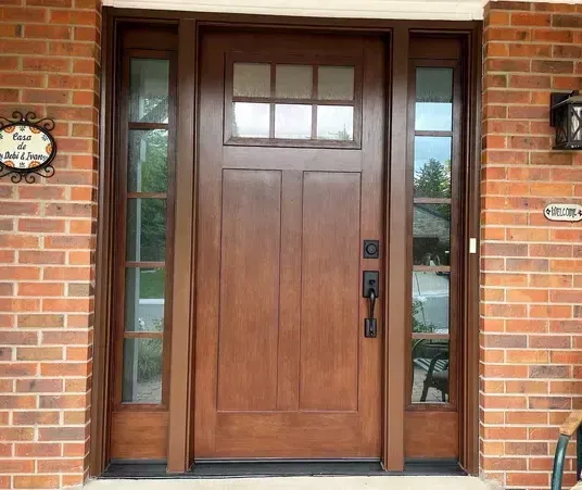 The front door of a brick house with a wooden door