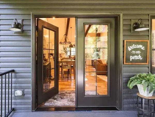 The front door of a house is open to a living room.