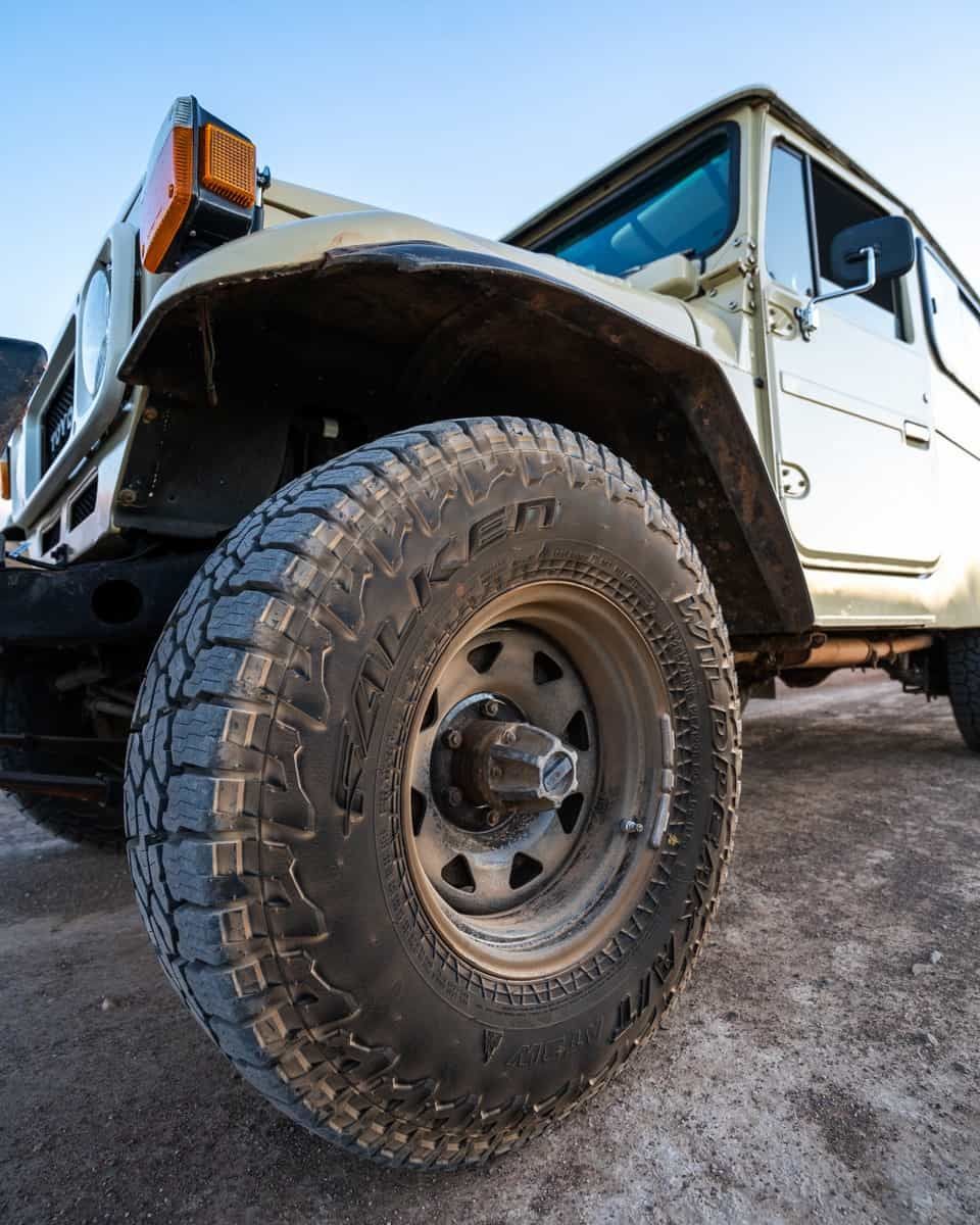 A Close Up Of A Jeep's Tire On A Dirt Road — Sojos Mechanical & Tyre Service In West Gosford, NSW