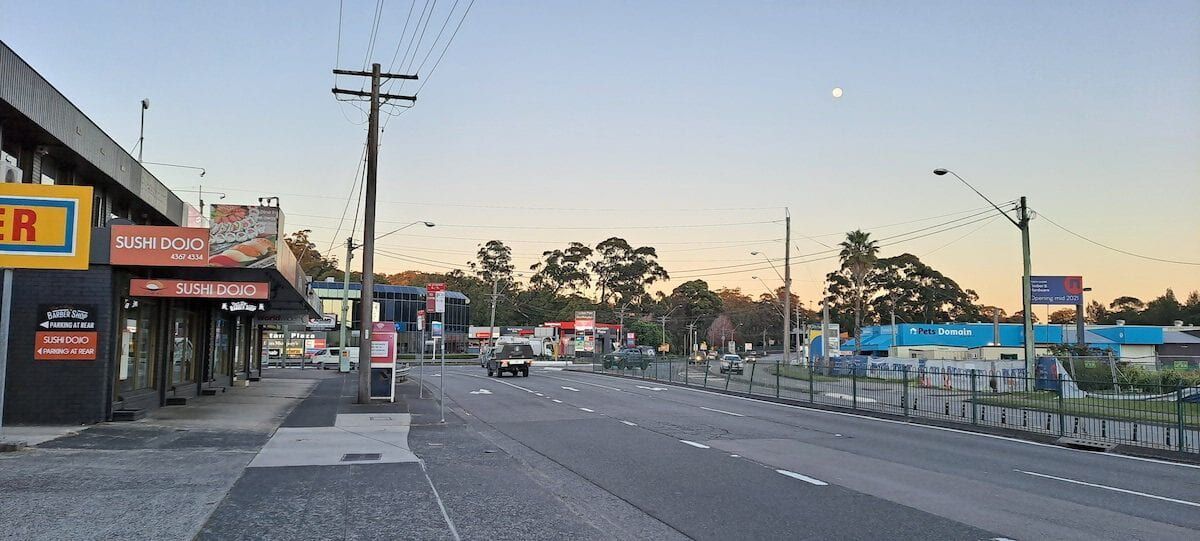 A Very Empty Street With A Lot Of Buildings And Trees In The Background — Sojos Mechanical & Tyre Service In Erina, NSW