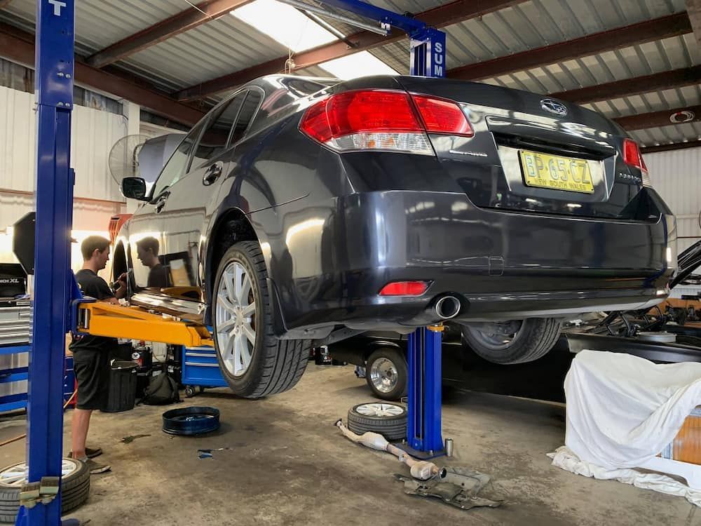 A Car Is Sitting On A Lift In A Garage — Sojos Mechanical & Tyre Service In West Gosford, NSW