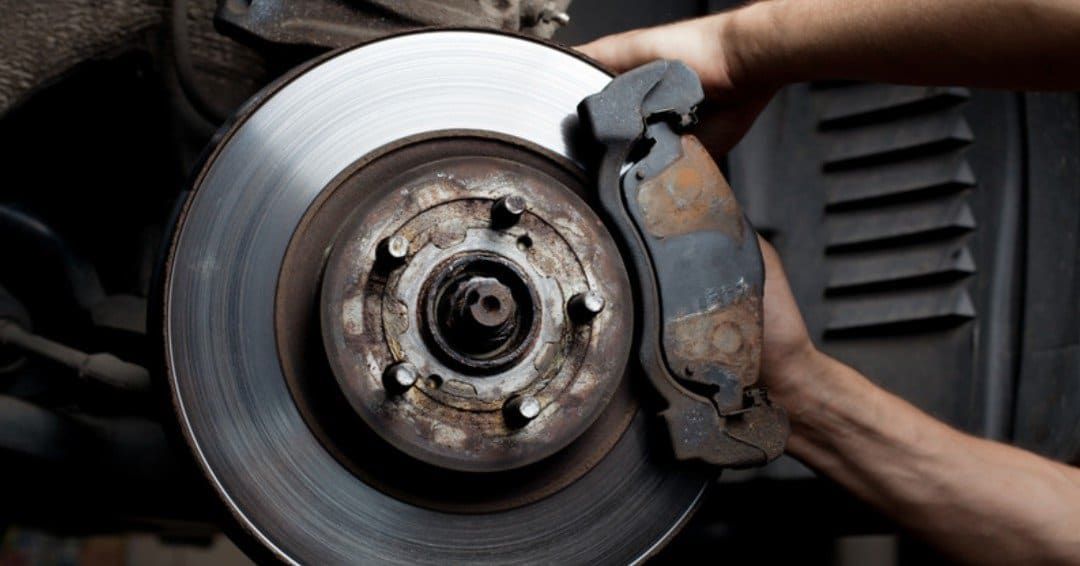 A Person Is Fixing A Brake Pad On A Car — Sojos Mechanical & Tyre Service In West Gosford, NSW