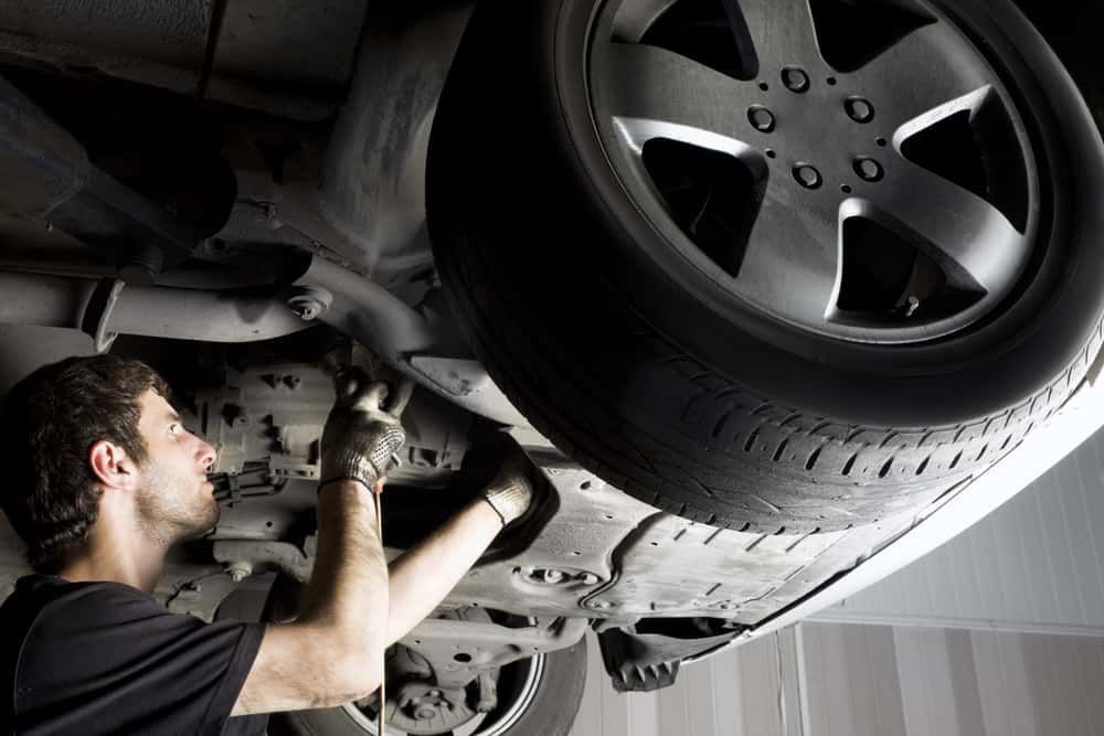 A Man Is Working On The Underside Of A Car — Sojos Mechanical & Tyre Service In Kariong, NSW