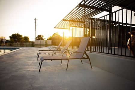 Sunlit rooftop patio with lounge chairs and pergola at sunset