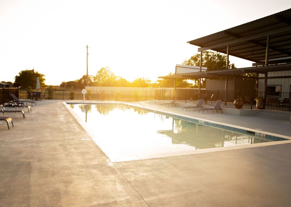 Outdoor swimming pool at sunset with lounge chairs and a shaded patio area