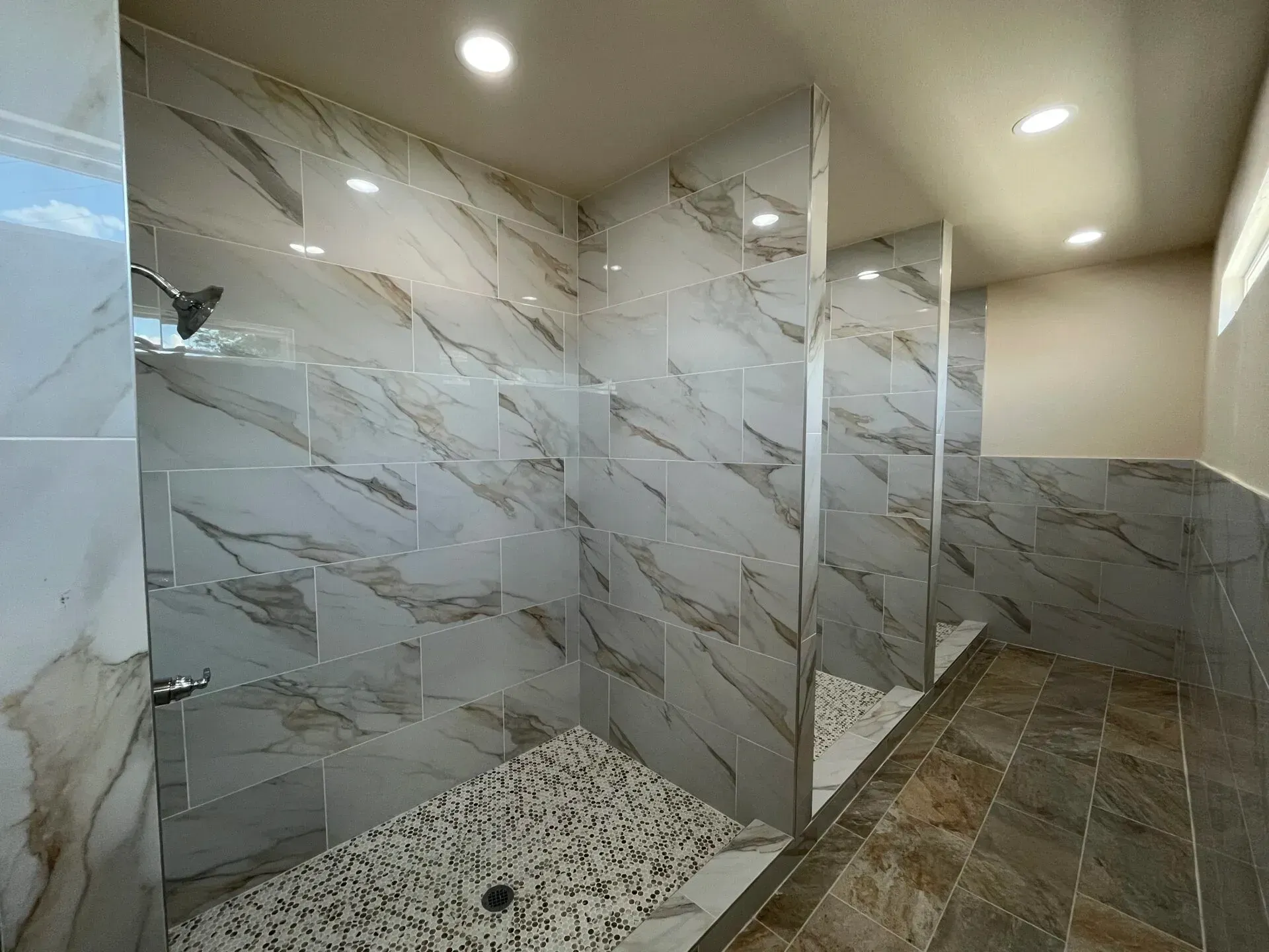 Narrow beige hallway with gray tile floor, recessed lights, white doors, and a bathroom vanity with mirror on the right