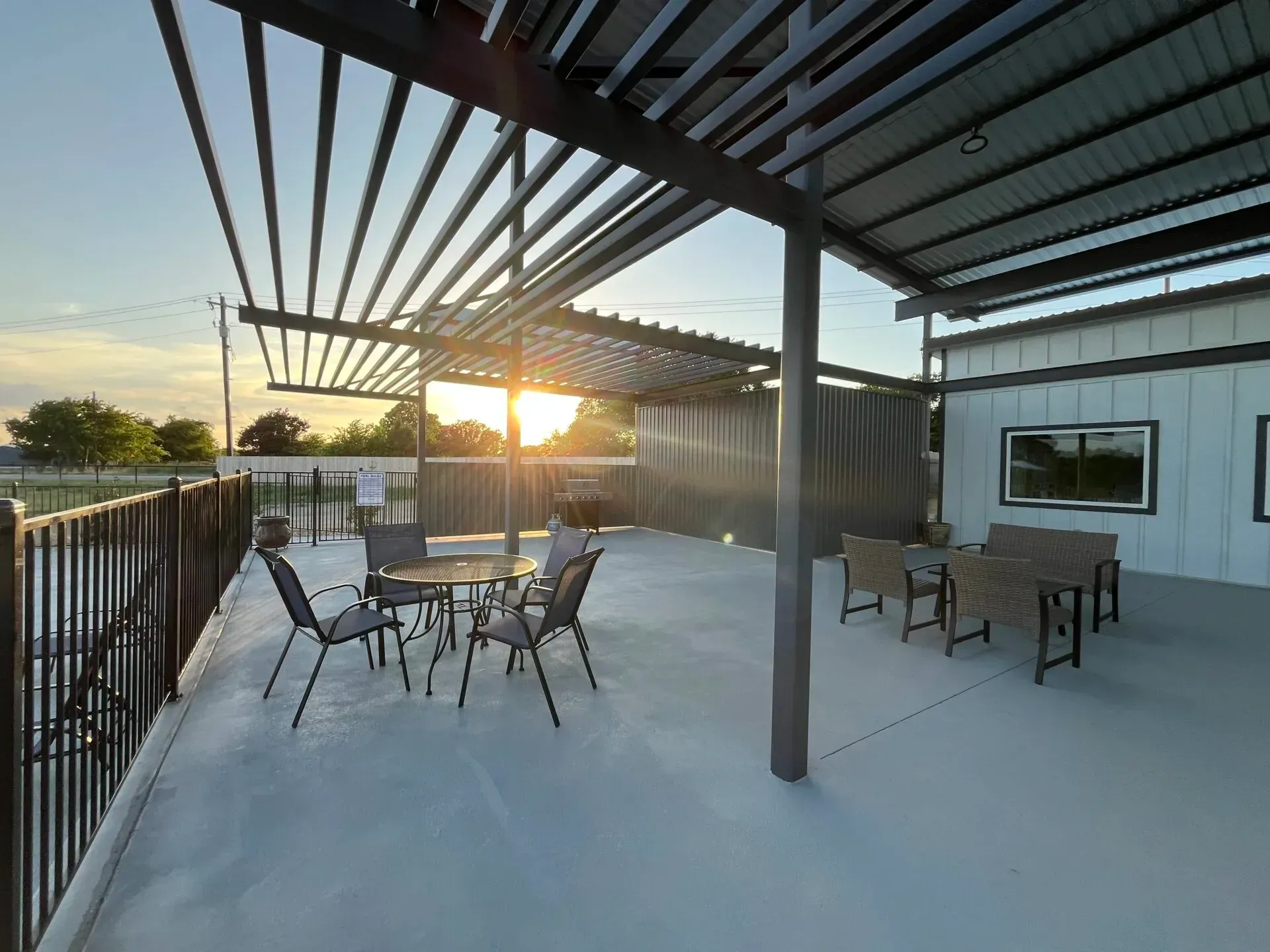 Covered patio with outdoor tables and chairs overlooking a sunset.