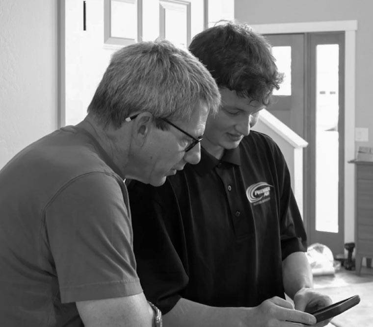 Man and teen looking at a phone together indoors, both focused.