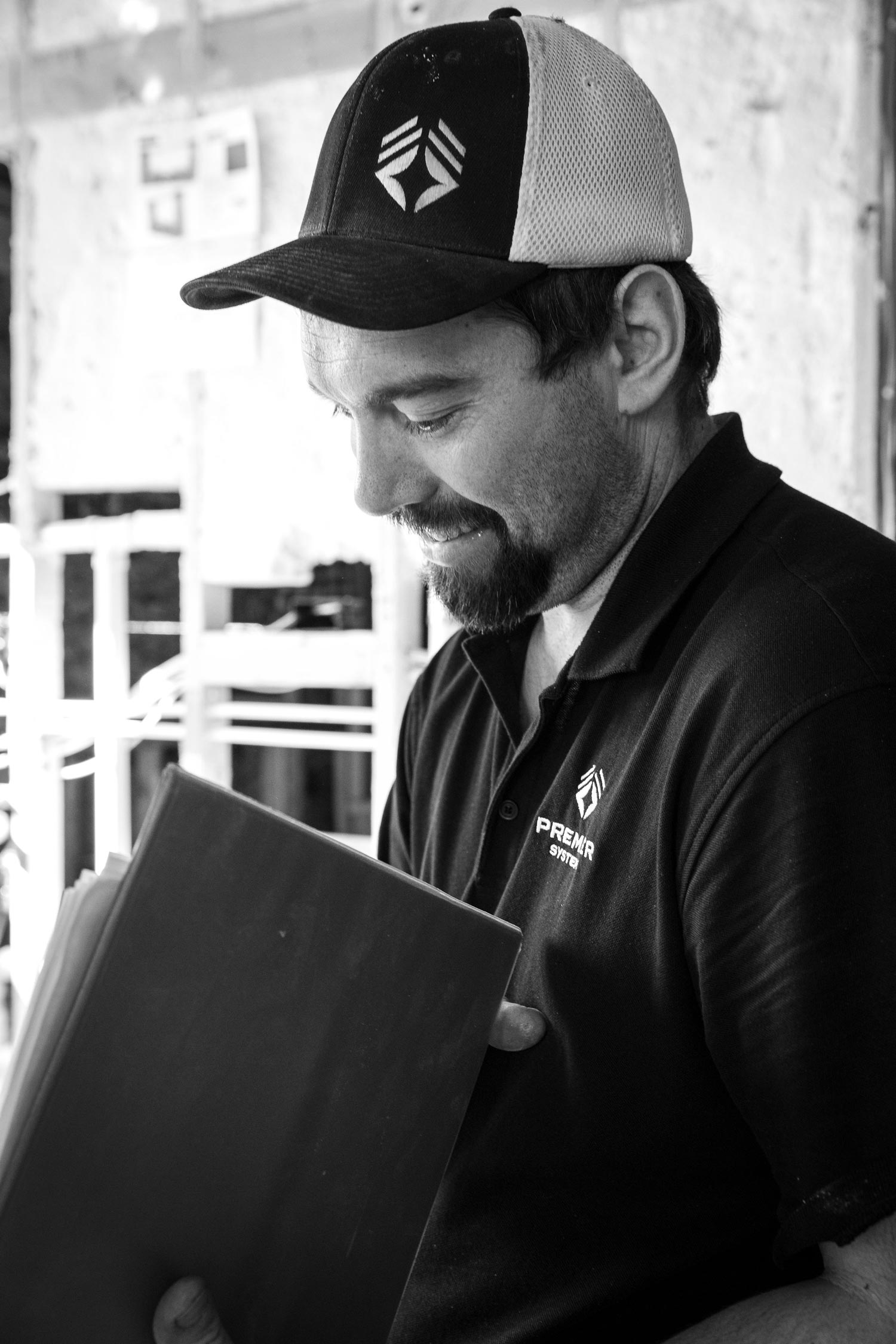 Man in a baseball cap and polo shirt looking at an object.