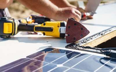 Worker using a yellow tool to repair solar panels on a rooftop