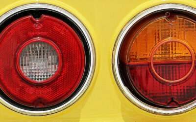 Close-up of two round red and amber vehicle tail lights on a yellow surface