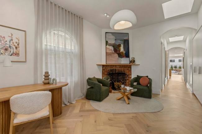 Bright living room with fireplace, arched ceiling, wood floors, round rug, and green lounge chairs