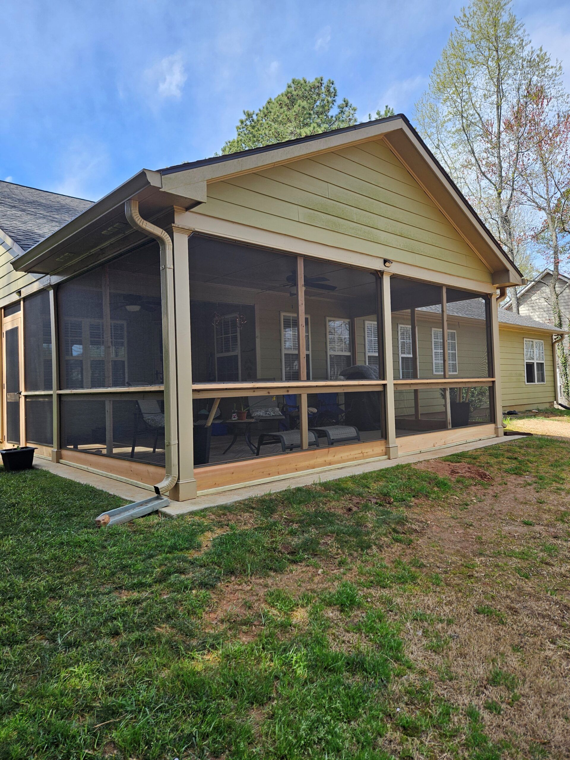A screened in porch is sitting in the backyard of a house.