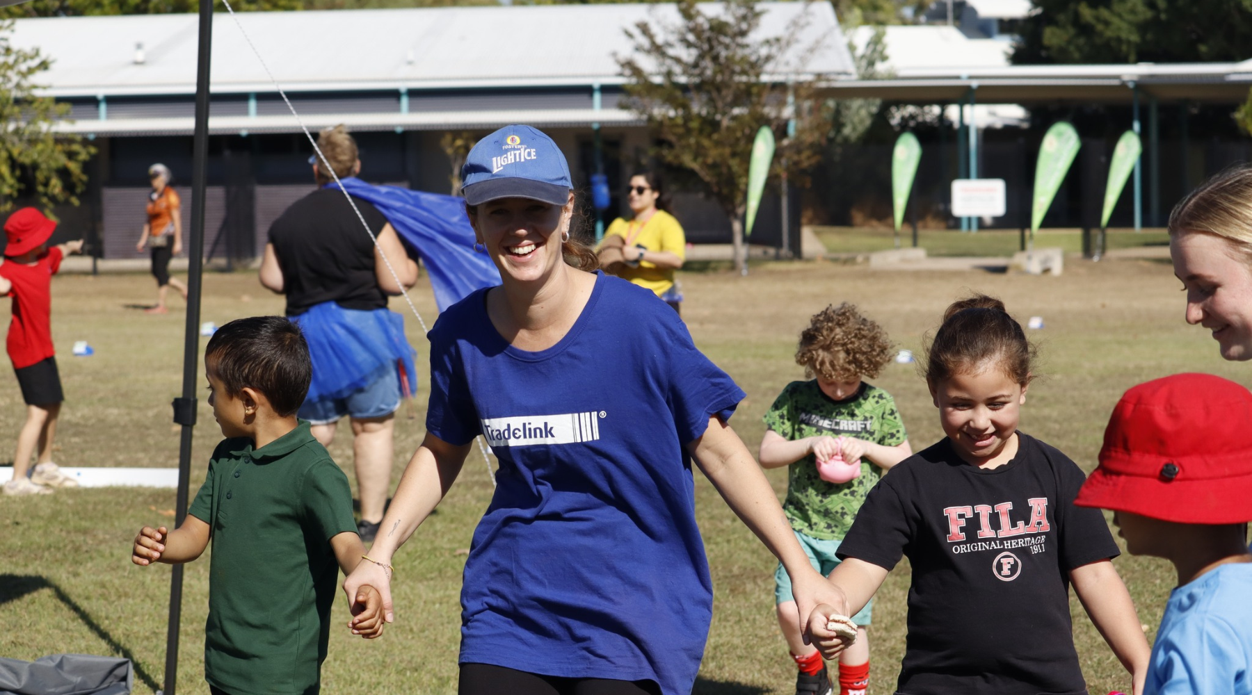 A woman in a fila shirt is walking with a group of children