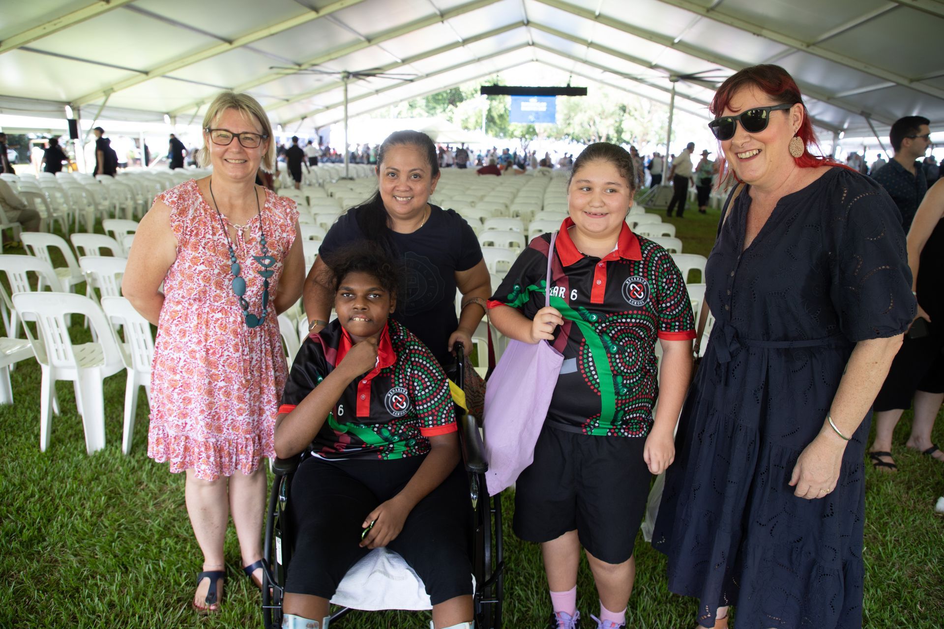 A group of women are standing next to a girl in a wheelchair.
