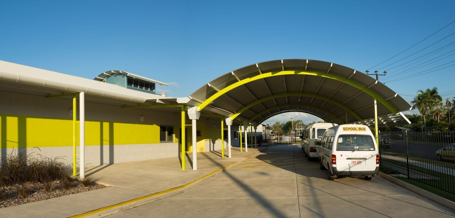 An ambulance is parked under a canopy in front of a building.