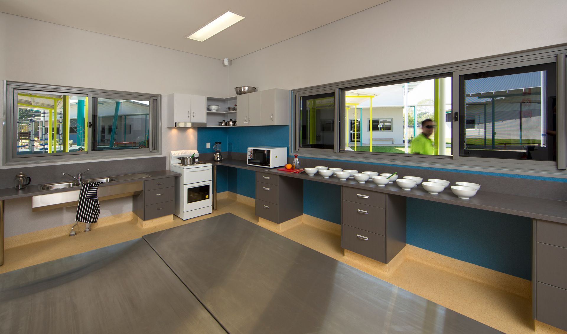 A kitchen with stainless steel appliances and a man standing in the window.