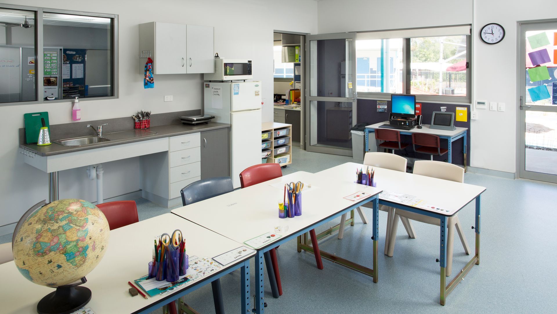A classroom with tables and chairs and a globe on the floor