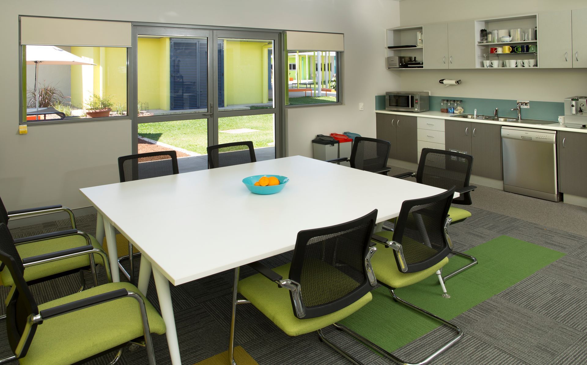 A kitchen with a table and chairs and a bowl of oranges on it
