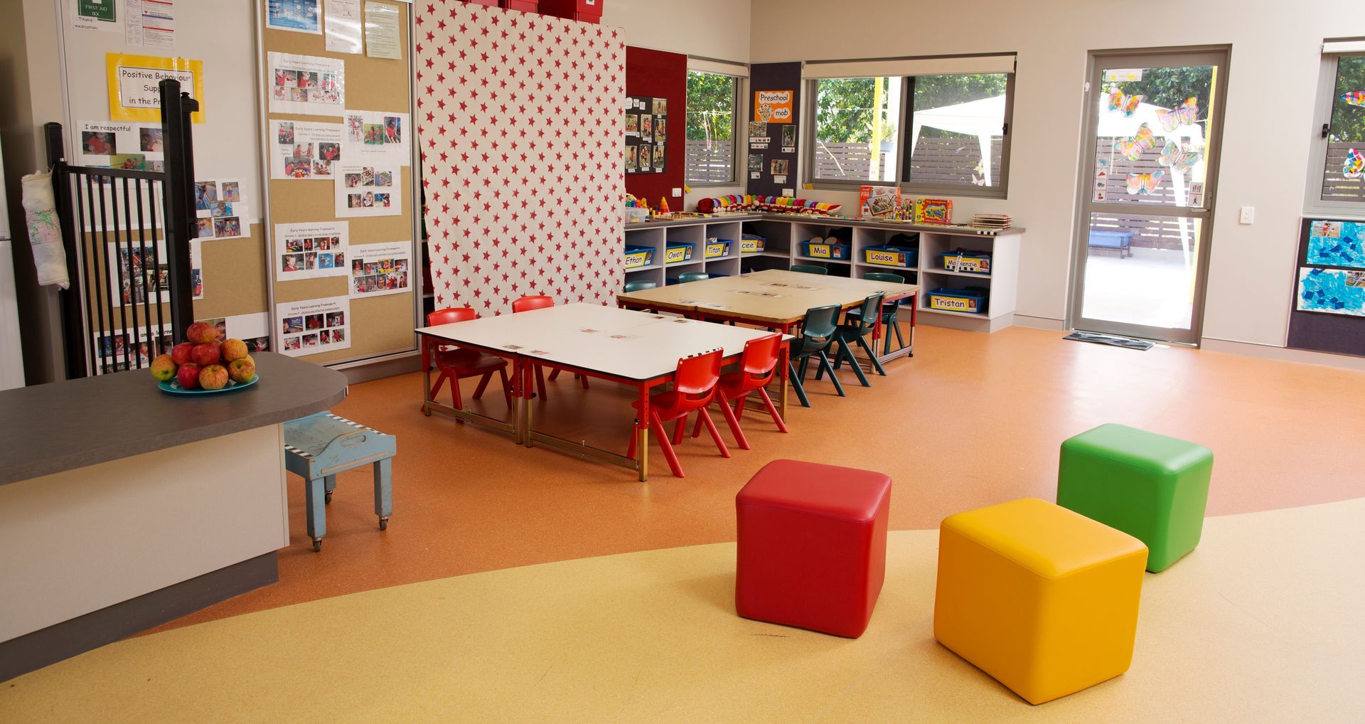 A classroom with tables and chairs and ottomans