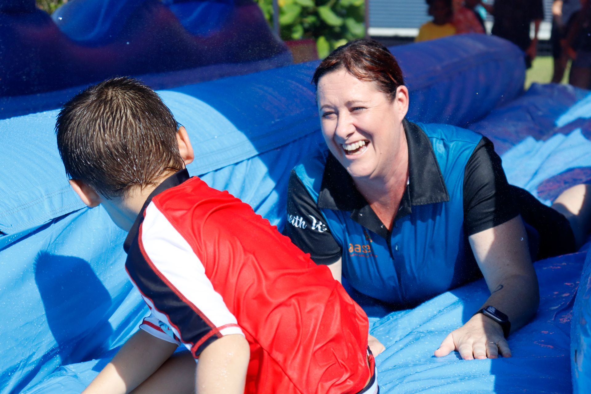 A woman and a boy are laying on a blue inflatable