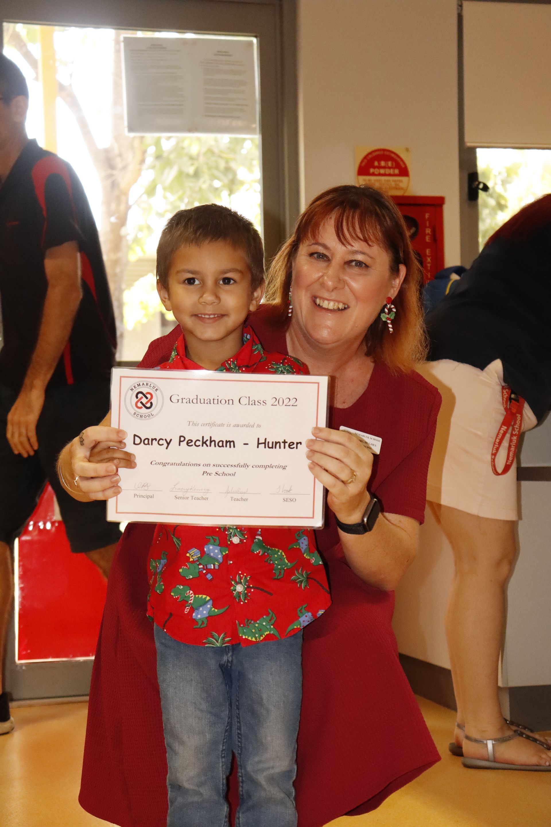A woman is holding a certificate next to a young boy