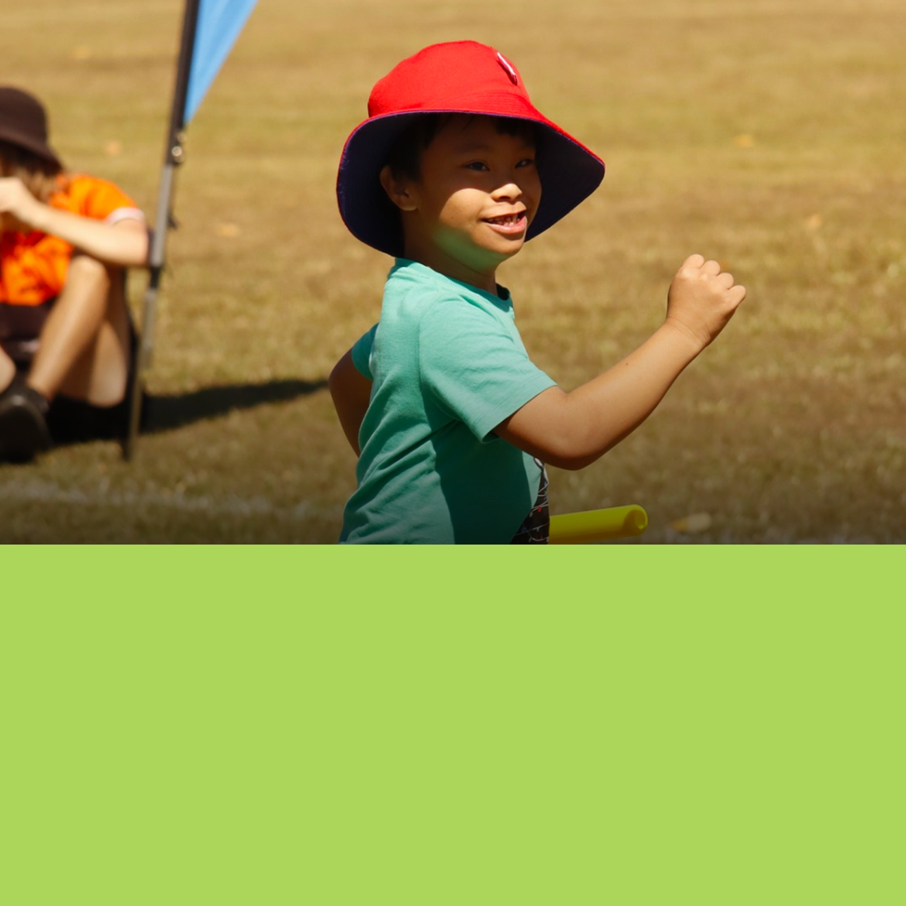 A young boy wearing a red hat is standing in a field