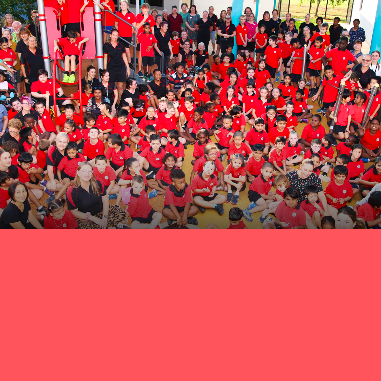 A large group of children in red shirts are posing for a picture