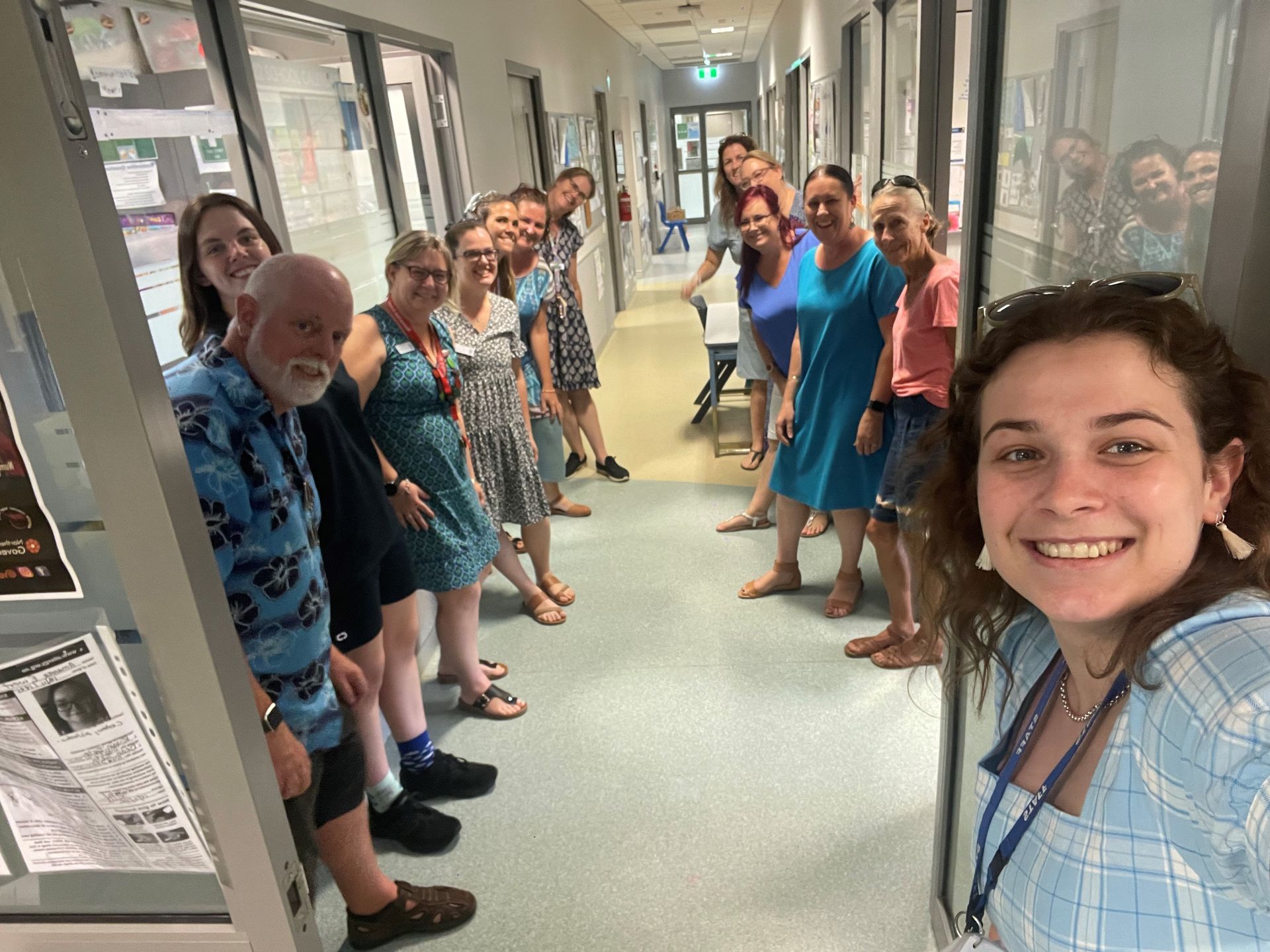 A group of people are posing for a picture in a hallway.