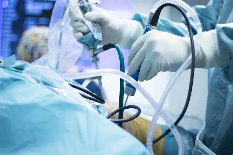 Surgeons in blue gloves using medical tools and tubing during an operation