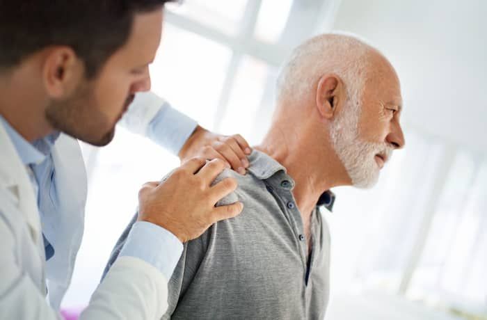 Doctor examining a patient’s shoulder in a bright clinic room