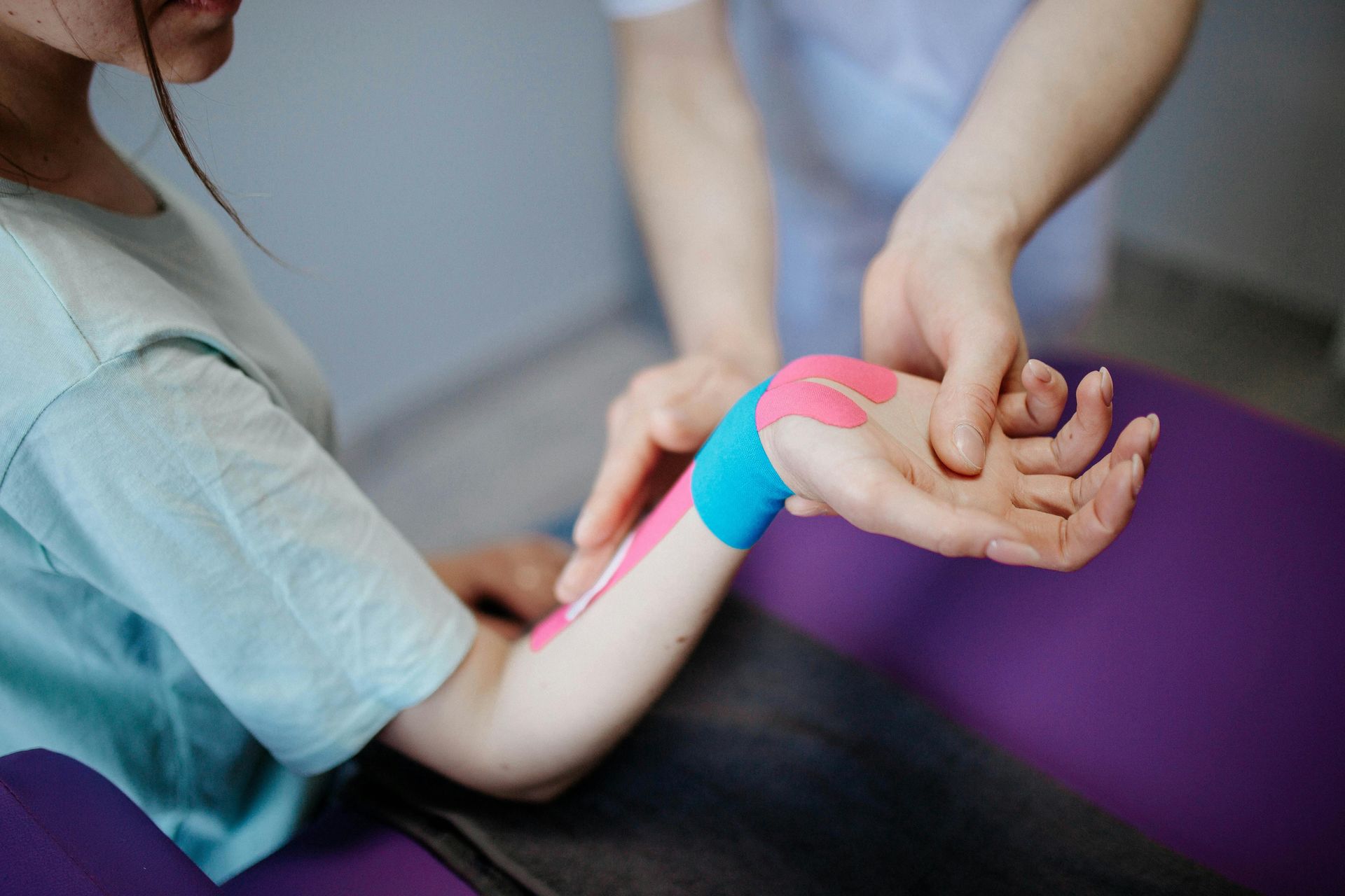 Child wearing colorful kinesiology tape on forearm during physical therapy treatment