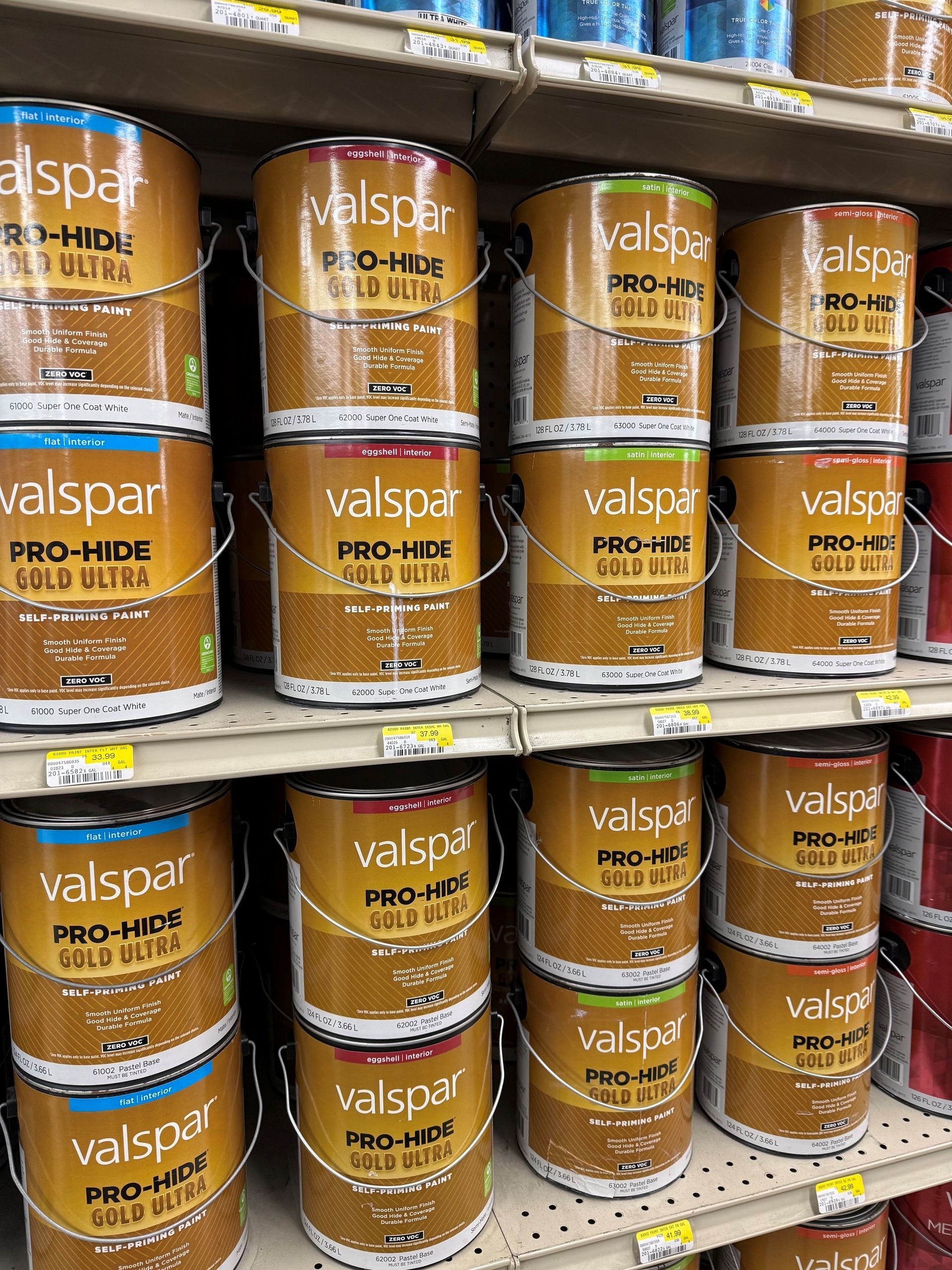 Shelf of stacked Valspar Pro-Hide paint cans in gold and white packaging