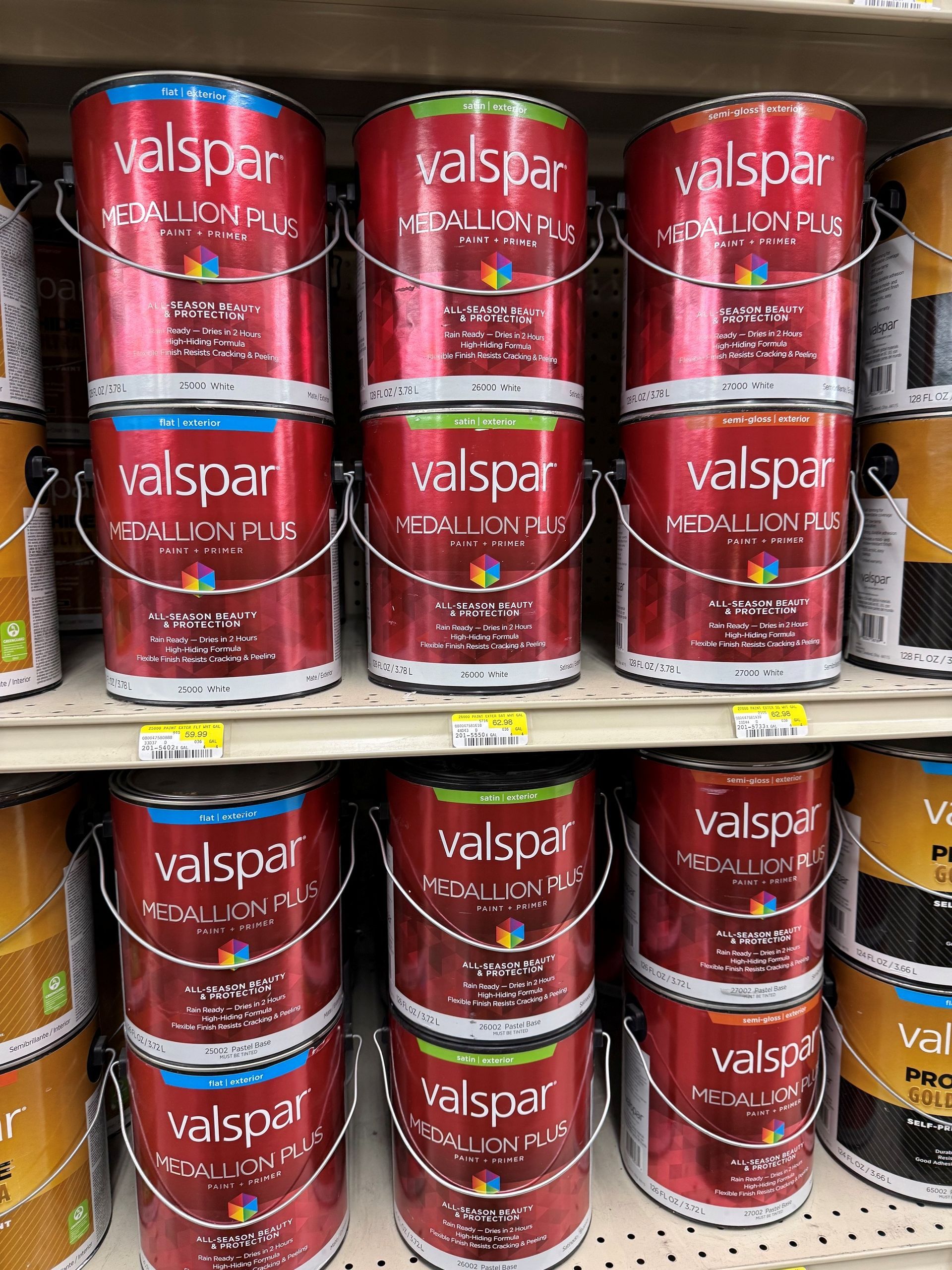 Stacks of red Valspar paint cans on store shelves with some yellow cans at the sides