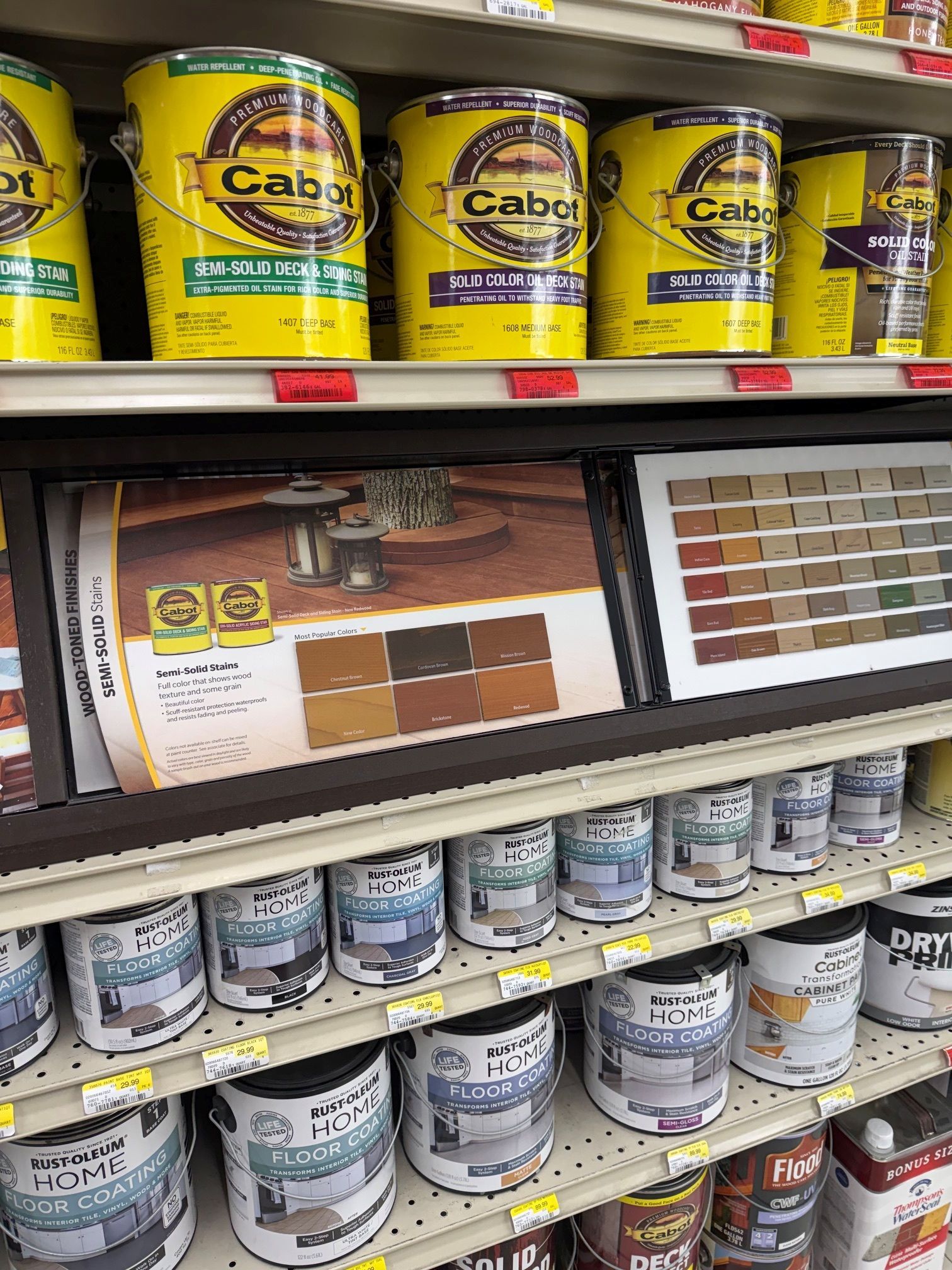 Paint cans on store shelves beside a paint color display board with swatches.