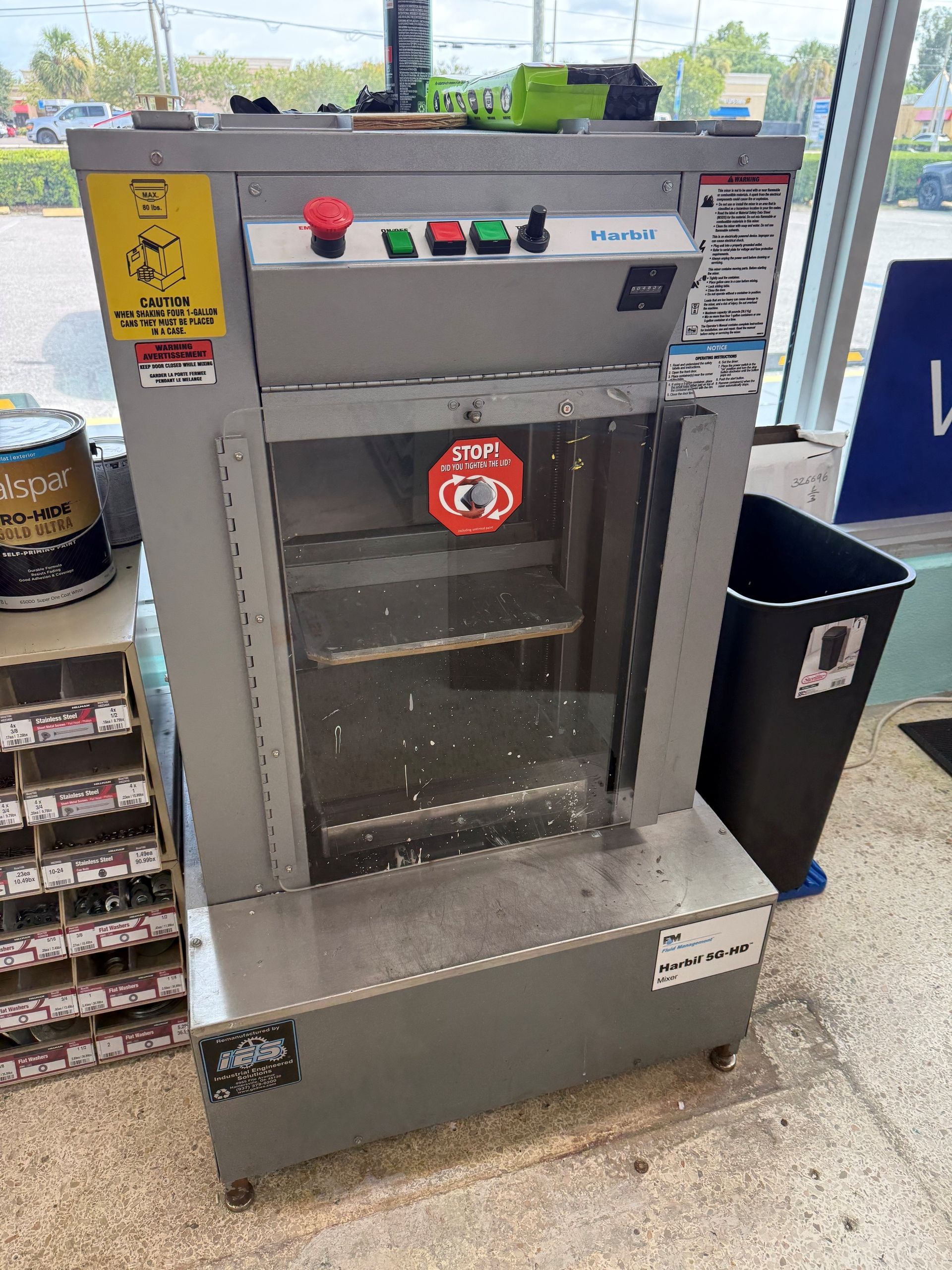 Metal industrial machine with red, green, and black controls beside a store entrance
