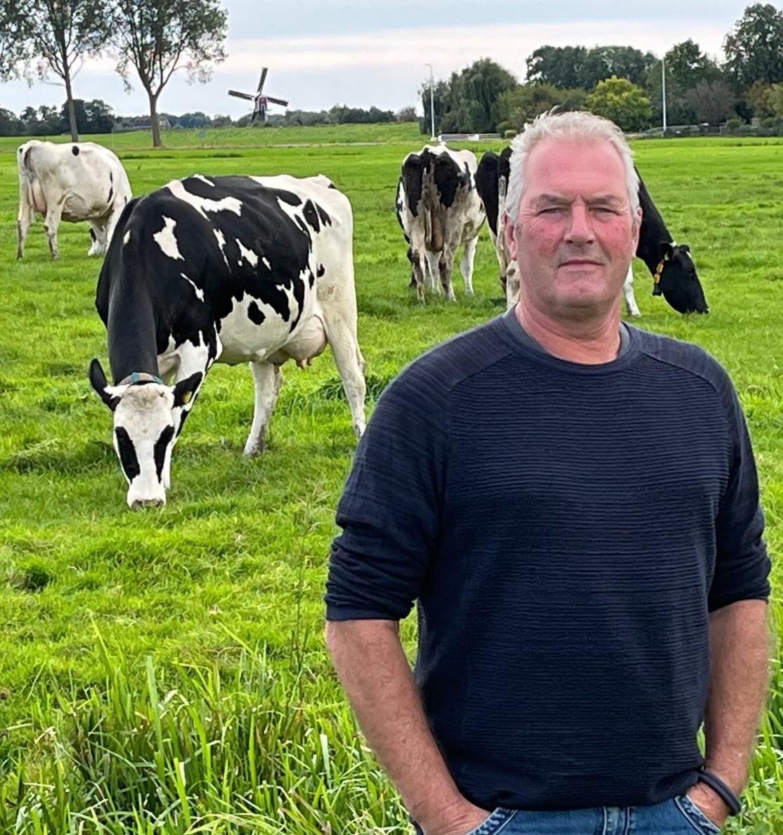 Portret van John van der Salm, voorzitter van boerenberaad GHN, in een weiland met zwartbonte melkkoeien.