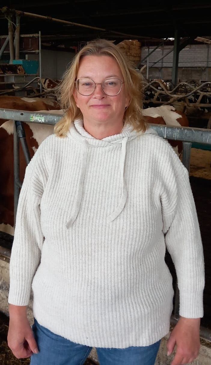 Portret van Marleen Verbeij, penningmeester van boerenberaad GHN, met op de achtergrond melkkoeien in de stal.