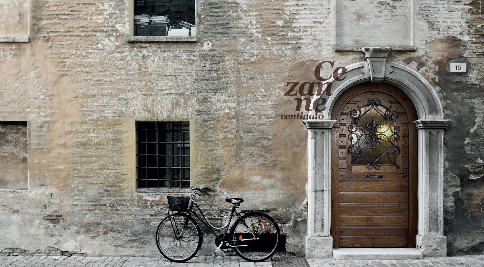 Vecchio muro di pietra con una bicicletta e un portale ad arco in legno in una scena di strada rustica