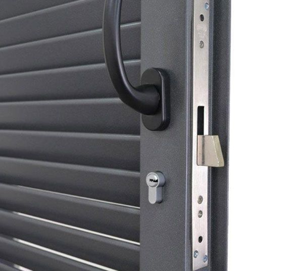 Porta blindata grigia con maniglia e meccanismo di chiusura neri (primo piano).