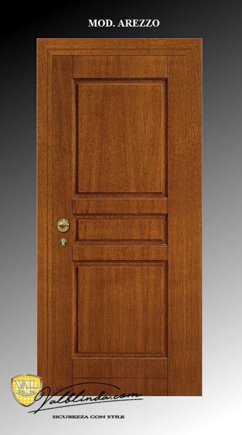 Porta d'ingresso con pannelli in legno, pomello e serratura in ottone, su sfondo grigio.