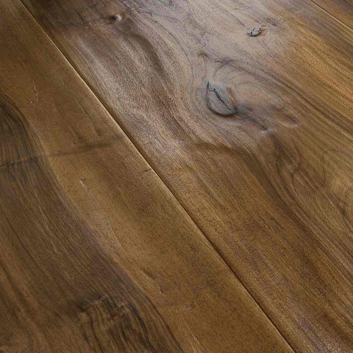 Primo piano di un pavimento in legno consumato dal tempo, con venature, nodi e assi disposte in diagonale ben visibili.