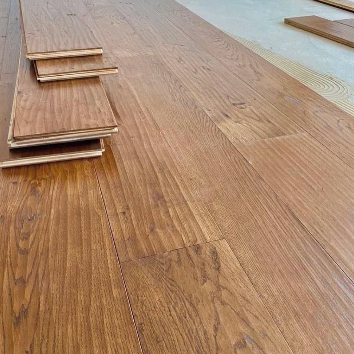 Tavole di legno impilate su un pavimento in legno durante l'installazione.