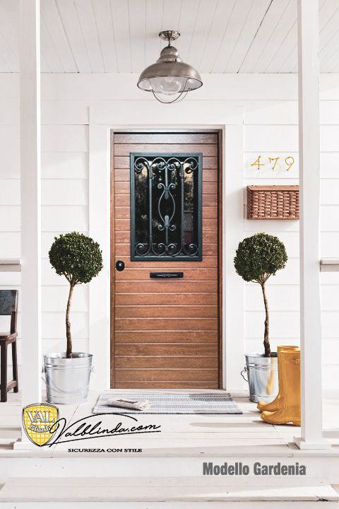 Ingresso principale con porta in legno, pannello in vetro e ferro nero, piante ornamentali in vaso e numero civico 479.