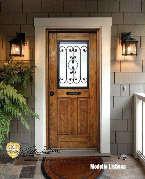 Porta d'ingresso in legno con pannelli decorativi in vetro, centrata su un portico in stucco color beige.