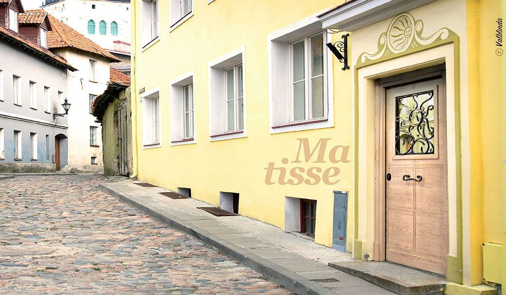 Strada deserta lastricata di ciottoli accanto a edifici color giallo pastello con una porta di legno decorativa