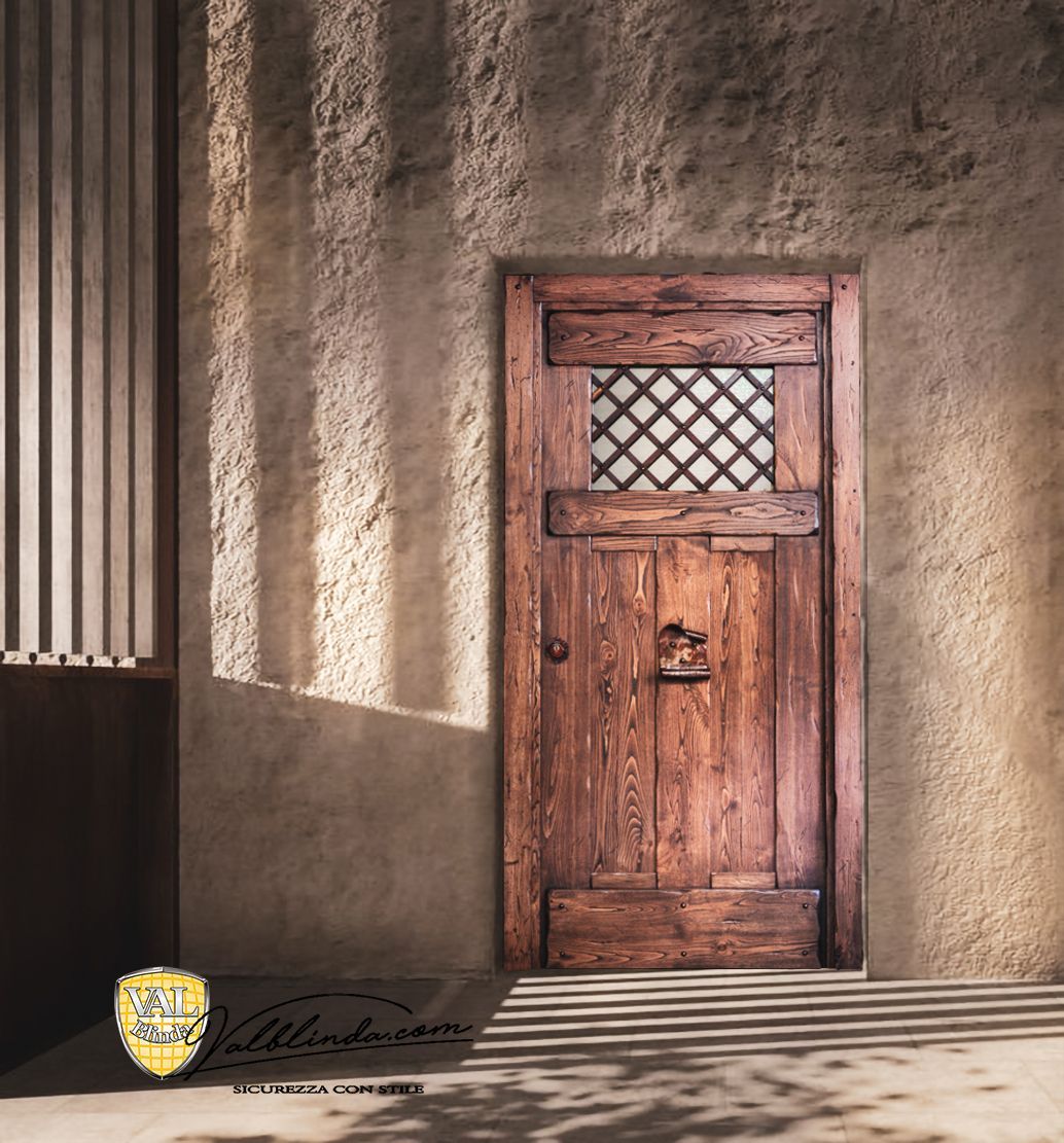 Porta rustica in legno in una parete intonacata e illuminata dal sole, con ombre striate e una piccola finestra a grata.