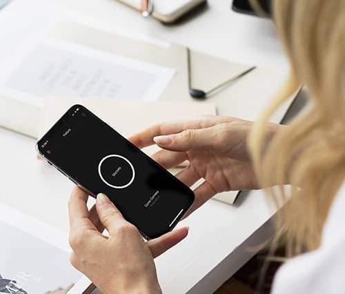 In un luminoso ufficio, una persona tiene in mano uno smartphone con la schermata del timer, seduta su una scrivania.