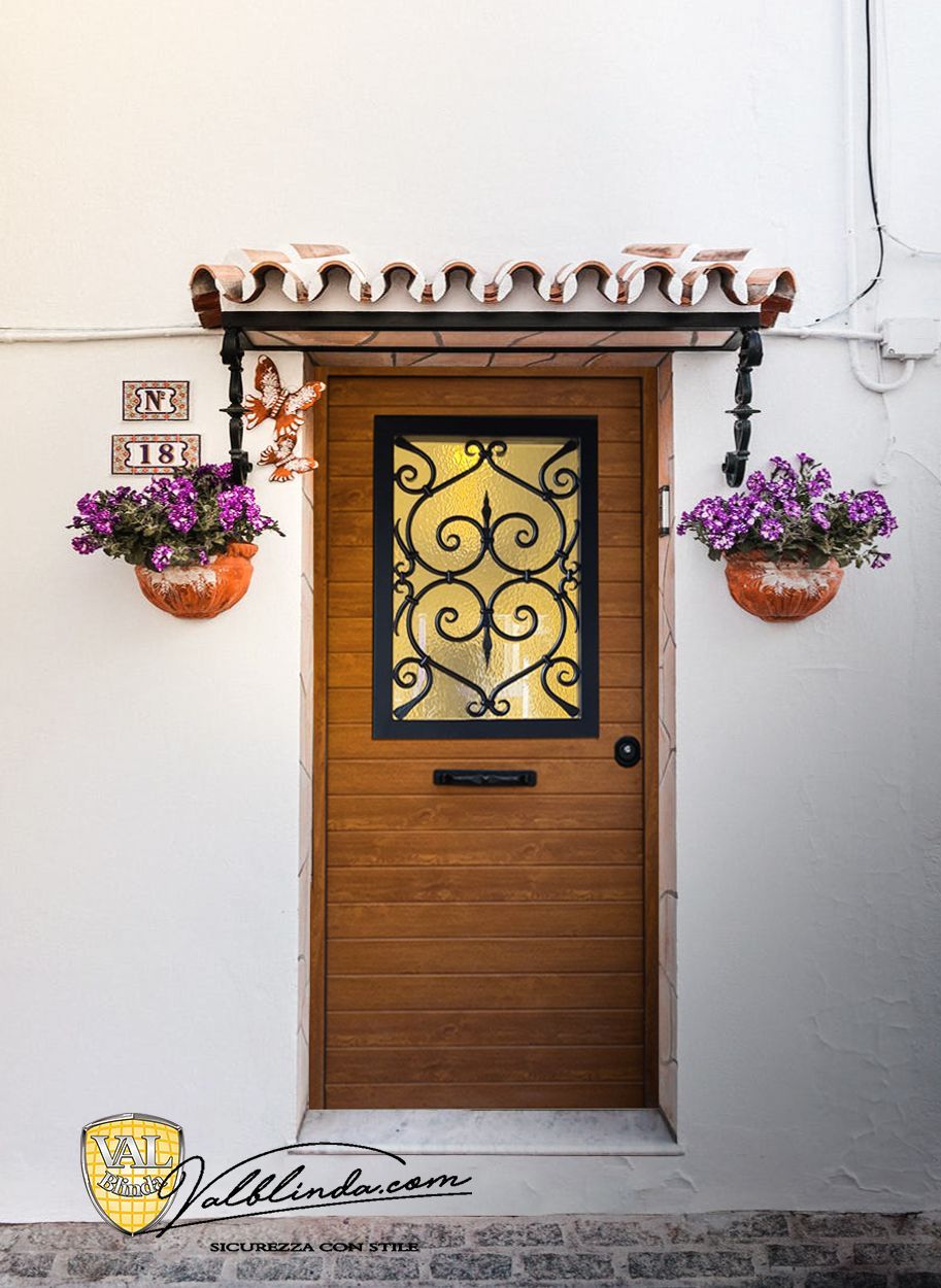Porta d'ingresso in legno con pannello in vetro decorato e cesti di fiori viola appesi a una parete bianca